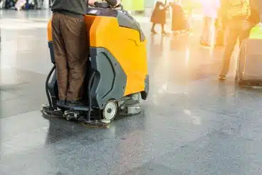 person operating floor cleaning machine for floor care purposes