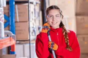 smiling woman wearing spectacles and a red jacket and holding a mop